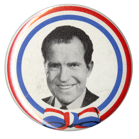 Round button edged in blue and red stripes. Black and white portrait of Richard Nixon.