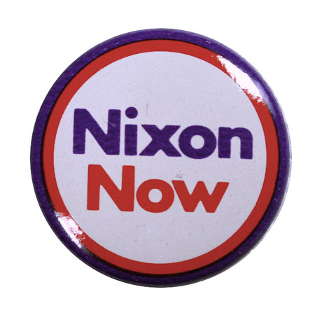 Round, white button edged in red and blue. Blue and red text reads "Nixon Now"