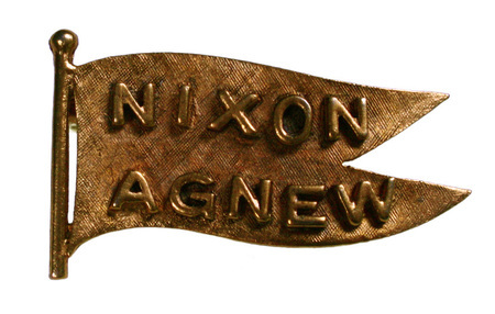 Flag-shaped gold pin with raised text reading "NIXON AGNEW"