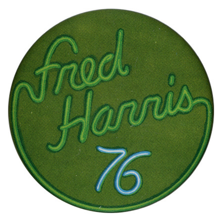 Round, green button with green and blue text in the style of a neon sign reading "Fred Harris 76"