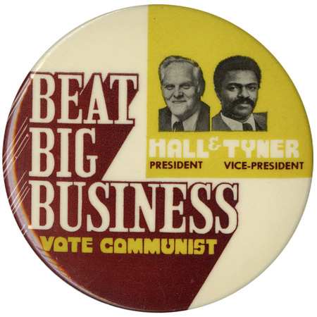 Round, white and yellow button with black and white portraits of Gus Hall and Jarvis Tyner. Stylized white, yellow, and black text reads "BEAT BIG BUSINESS VOTE COMMUNIST HALL PRESIDENT & TYNER VICE-PRESIDENT"
