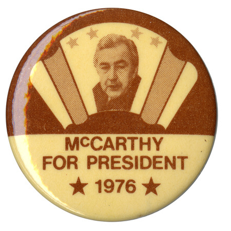 Round, white and brown button with a portrait of Eugene McCarthy within a scroll decoration. Brown text reads "McCARTHY FOR PRESIDENT 1976"