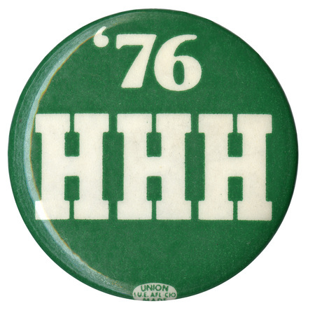 Round, green button with white text reading "'76 HHH"