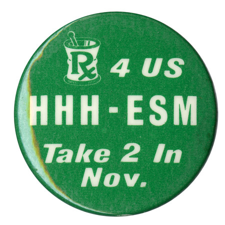 Round, green button with a drawing of a mortar and pestle in white. Green and white text reads "Rx 4 US HHH-ESM Take 2 In Nov."