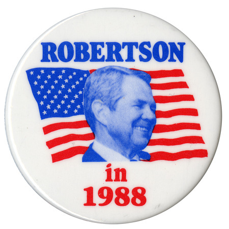 Round, white button with a blue and white photograph of Pat Robertson against a red, white, and blue flag. Blue and red text reads "ROBERTSON in 1988"