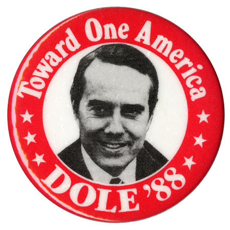 Round button with a red border and a black and white photograph of Bob Dole in the center. White text reads "Toward One America DOLE '88"