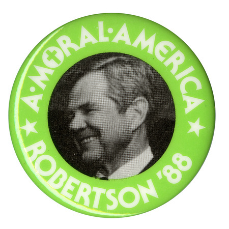 Round button with a green border and a black and white photograph of Pat Robertson in the center. White text reads "A MORAL AMERICA ROBERTSON '88". The "O" in "MORAL" contains a Christian cross.
