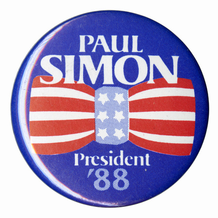 Round, blue button with a drawing of a red, white, and blue bowtie in the center. White text reads "PAUL SIMON President '88"