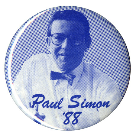 Round, blue and white button with a photograph of Paul Simon and blue text reading "Paul Simon '88"