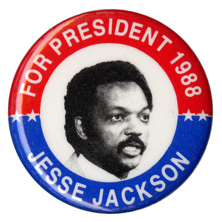 Round button with red and blue border and a black and white photograph of Jesse Jackson in the center. White text reads "FOR PRESIDENT 1988 JESSE JACKSON"