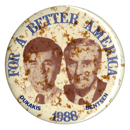 Round, whitish button with black and white portraits of Michael Dukakis and Lloyd Bentsen. Blue text reads "FOR A BETTER AMERICA DUKAKIS 1988 BENTSEN"