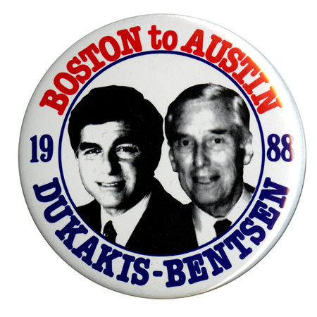 Round, white button with black and white photographs of Michael Dukakis and Lloyd Bentsen. Red and blue text reads "BOSTON to AUSTIN 1988 DUKAKIS-BENTSEN"