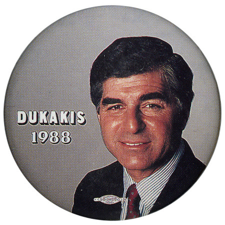Round, gray button with a color photograph of Michael Dukakis. White text reads "DUKAKIS 1988"