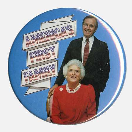 Round, blue button with a color photograph of George H. W. and Barbara Bush. A white ribbon bears red and blue text reading "AMERICA'S FIRST FAMILY"