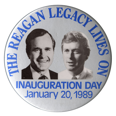 Round, silver button with black and white photographs of George H. W. Bush and Dan Quayle. Blue text reads "THE REAGAN LEGACY LIVES ON INAUGURATION DAY January 20, 1989"