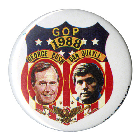 Round, white button with an elaborate red, white, blue, and gold shield decoration containing color photographs of George H. W. Bush and Dan Quayle, each with his name above his photograph. Blue and gold text reads "GOP 1988"