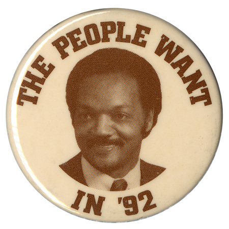 Round, white button with a black and white photograph of Jesse Jackson. Black text reads "THE PEOPLE WANT IN '92"