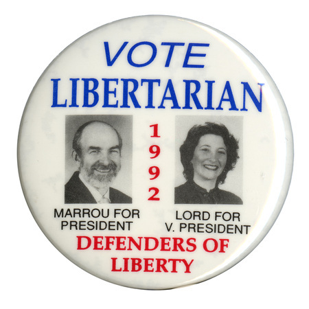 Round, white button with black and white photographs of Andre Marrou and Nancy Lord. Blue, red, and black text reads "VOTE LIBERTARIAN 1992 MARROU FOR PRESIDENT LORD FOR V. PRESIDENT DEFENDERS OF LIBERTY"
