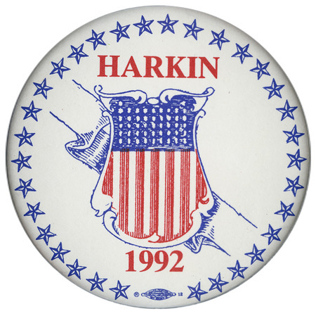 Round, white button with a border of blue stars and an elaborate shield decoration in the center. Red text reads "HARKIN 1992"