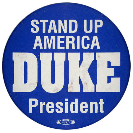 Round, blue button with white text reading "STAND UP AMERICA DUKE President"