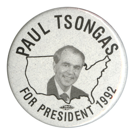 Round, gray button with a black and white photograph of Paul Tsongas against a black outline of the United States. Black text reads "PAUL TSONGAS FOR PRESIDENT 1992"