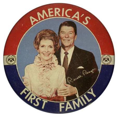 Round button with red and blue border and a color photograph of Nancy and Ronald Reagan in the center. White text reads "AMERICA'S FIRST FAMILY". 