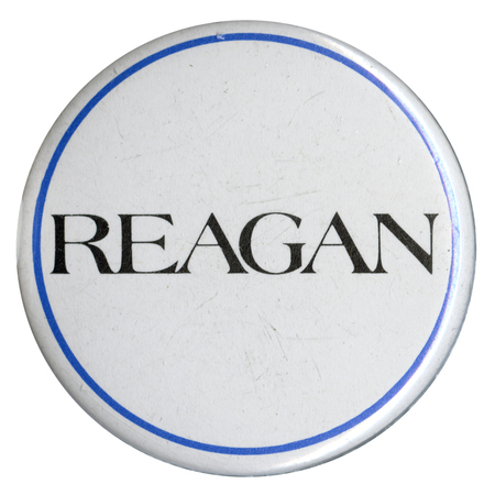 Round, white button with a blue border and black text reading "REAGAN"
