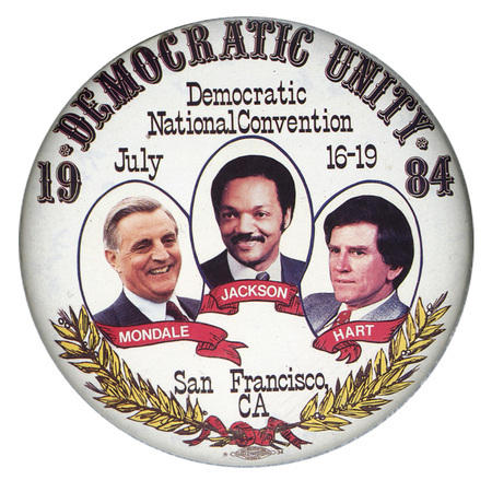 Round, white button with color photographs of Walter Mondale, Jesse Jackson, and Gary Hart above a drawing of olive branches connected by a red ribbon. Text reads "DEMOCRATIC UNITY 1984 Democratic National Convention July 16-19 MONDALE JACKSON HART San Francisco, CA"