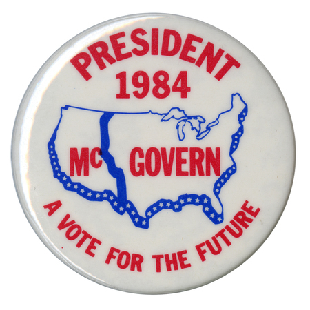 Round, white button with a blue outline of the United States with a blue line down the center of the country's western half. Red text reads "PRESIDENT 1984 McGOVERN A VOTE FOR THE FUTURE"