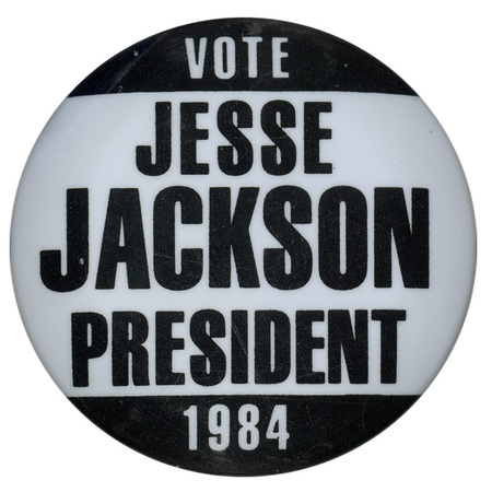 Round, black and white button with contrasting white and black text reading "VOTE JESSE JACKSON PRESIDENT 1984"