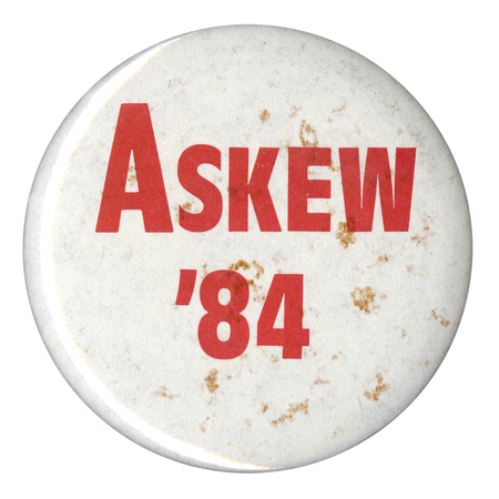 Round, white button with red text reading "ASKEW '84"