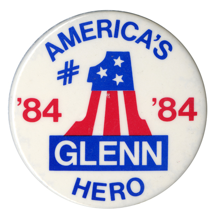 Round, white button with red and blue text reading "AMERICA'S #1 HERO GLENN '84 '84." 
