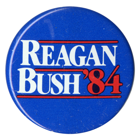 Round, blue button with white and red text reading "REAGAN BUSH '84"
