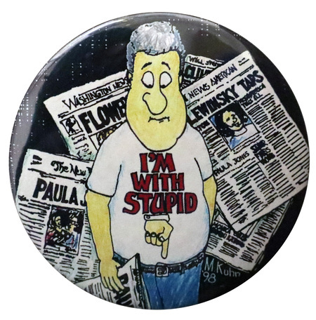 Round button with a cartoon illustration of Bill Clinton against a background of newspapers with headlines including the words "PAULA," "FLOWERS," and "LEWINSKY TAPS." On Clinton's shirt is red text reading "I'M WITH STUPID" and an image of a hand pointing to Clinton's crotch.