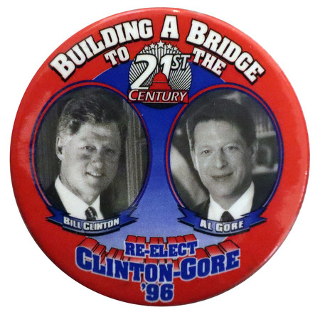 Round button with a red border and a blue center. Black and white photographs of Bill Clinton and Al Gore appear in circles, each with his name under his photograph. White and blue text reads "BUILDING A BRIDGE TO THE 21st CENTURY. RE-ELECT CLINTON-GORE '96"