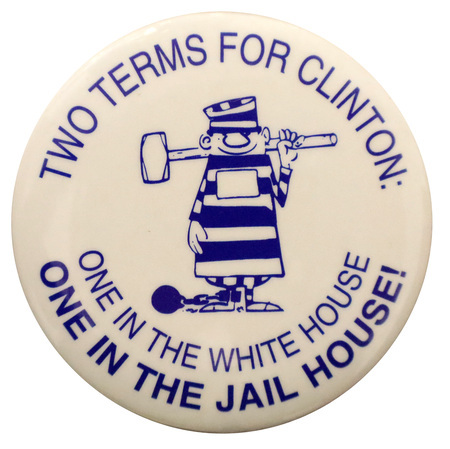 Round, white button with a blue cartoon illustration of a person wearing a striped prisoner's outfit, holding a sledgehammer, a ball and chain attached to one leg. Blue text reads "TWO TERMS FOR CLINTON: ONE IN THE WHITE HOUSE ONE IN THE JAIL HOUSE!"