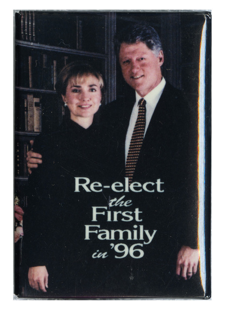 Rectangular button with a color photograph of Hillary and Bill Clinton and white text reading "Re-elect the First Family in '96"