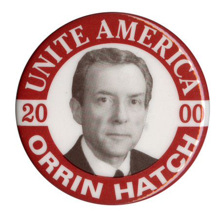 Round, white button with a maroon border and a black and white photograph of Orrin Hatch in the center. White text reads "UNITE AMERICA 2000 ORRIN HATCH"