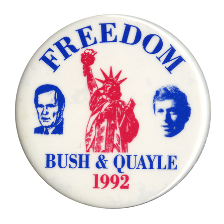 Round, white button with blue drawings of George H. W. Bush and Dan Quayle and a red drawing of the Statue of Liberty. Blue and red text reads "FREEDOM BUSH & QUAYLE 1992"