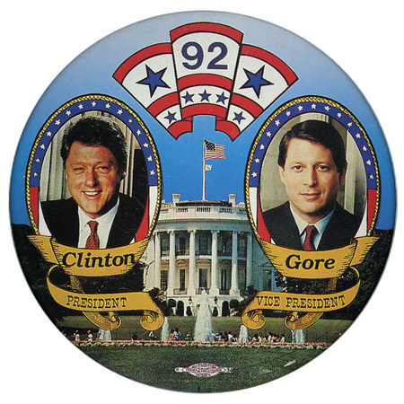 Round button with color photographs of Bill Clinton and Al Gore in flag-themed frames against a color photograph of the White House. Hovering above is a scroll-shaped drawing with "92" written in it. Below the candidates' photographs is black text reading "Clinton PRESIDENT Gore VICE PRESIDENT"