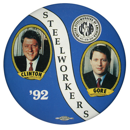 Round, blue button with a band of white through the middle and color photographs of Bill Clinton and Al Gore, each with his name below his photograph. The seal of the United Steelworkers of America AFL-CIO-CLC appears near the top. Black and white text read "'92 STEELWORKERS"