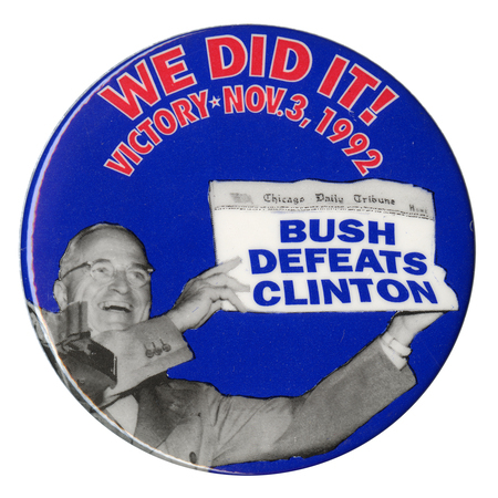 Round, blue button with a black and white photograph of Harry Truman holding up a newspaper in which the original "DEWEY DEFEATS TRUMAN" text of 1948 has been replaced with "BUSH DEFEATS CLINTON." Red text on the button reads "WE DID IT! VICTORY NOV. 3, 1992"
