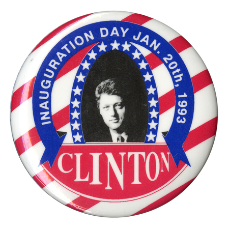 Round, red and white striped button with a black and white photograph of Bill Clinton in the center surrounded by blue ribbons and stars. White text reads "INAUGURATION DAY JAN. 20th, 1993 CLINTON"