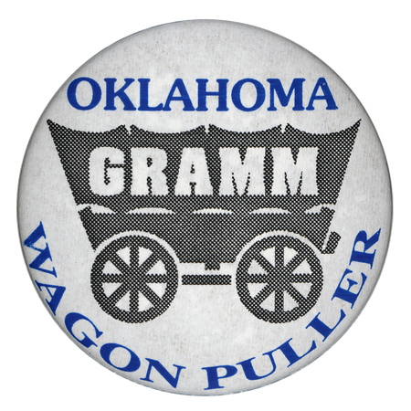 Round, white button with a black drawing of a covered wagon with white text reading "GRAMM". Blue text reads "OKLAHOMA WAGON PULLER"