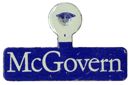 Blue, fold over lapel pin with white text reading "McGovern"