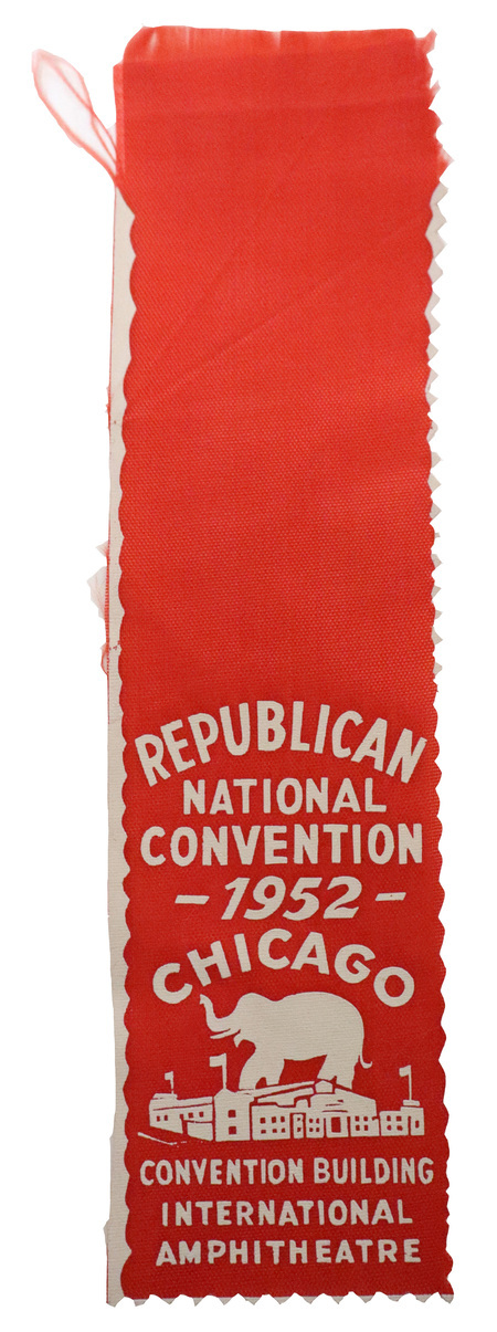 Red ribbon with a white illustration of an elephant rising above the Chicago International Amphitheatre and white text reading "REPUBLICAN NATIONAL CONVENTION 1952 CHICAGO CONVENTION BUILDING INTERNATIONAL AMPHITHEATRE"
