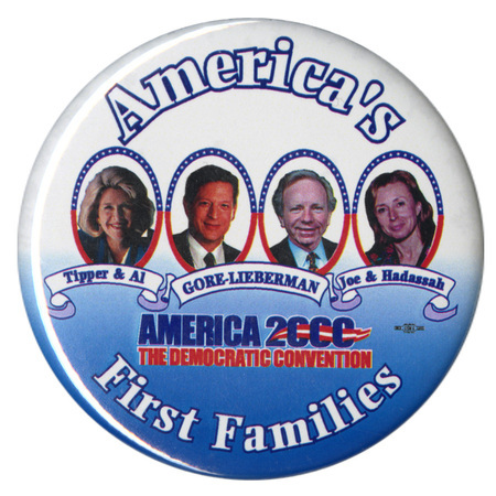 Round, white and blue button with color photographs of Tipper Gore, Al Gore, Joe Lieberman, and Hadassah Lieberman. White, red, and blue text reads "America's First Families Tipper & Al GORE-LIEBERMAN Joe & Hadassah AMERICA 2000 THE DEMOCRATIC CONVENTION"