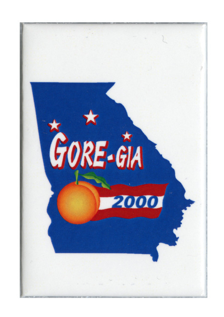 Rectangular, white button with a solid blue outline of the state of Georgia containing white stars, a yellow peach, and a red and white banner. White and blue text reads "GORE-GIA 2000"