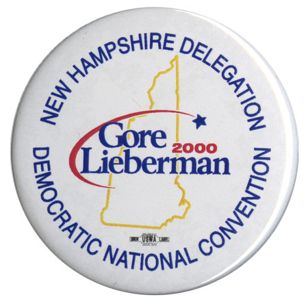 Round, white button with a yellow outline of the state of New Hampshire. Blue and red text reads "NEW HAMPSHIRE DELEGATION Gore Lieberman 2000 DEMOCRATIC NATIONAL CONVENTION"