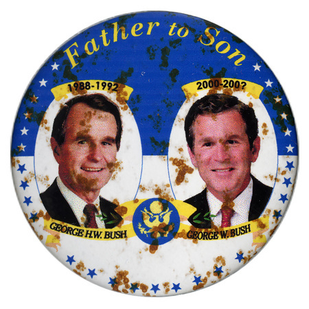 Round, blue and white button with color photographs of George H. W. Bush and George W. Bush. Yellow and black text reads "Father to Son 1988-1992 GEORGE H. W. BUSH 2000-200? GEORGE W. BUSH"